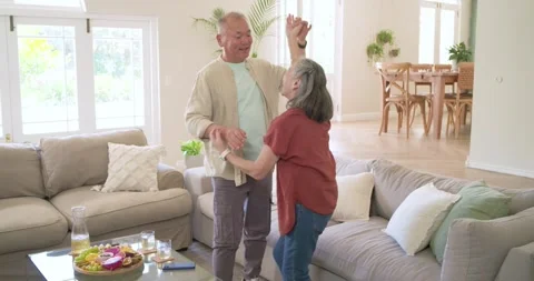 Senior couple sharing affection, dancing in living room with man leading gentle Stock Footage 341468153