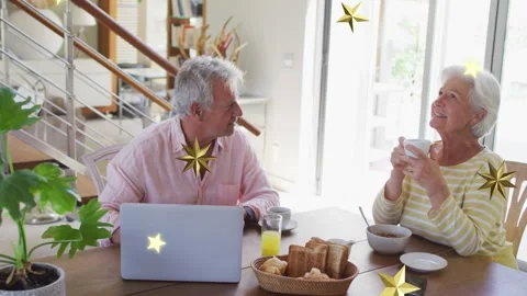 Senior couple sharing AM man glancing while laptop-led stars floating over table Vídeo Stock 334322305