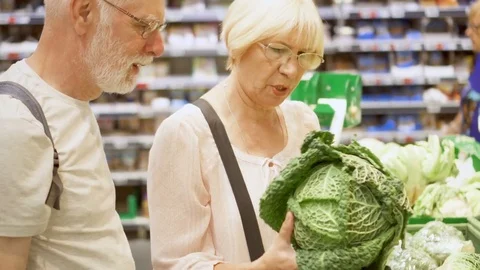 Senior couple shopping in grocery store. Standing in vegetable department Stock Footage