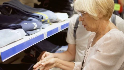 Senior couple shopping in mall, choosing jeans. Family in store picking and Stock Footage