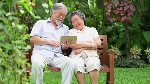 Senior couple sitting and using tablet together in home garden. Stock Footage 98383171