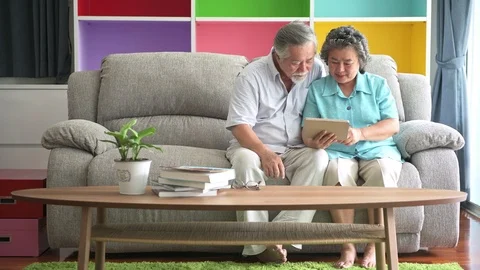 Senior couple sitting and watching tablet in living room. Stock Footage