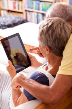Senior couple sitting on couch using digital tablet, partial view Stock Photos