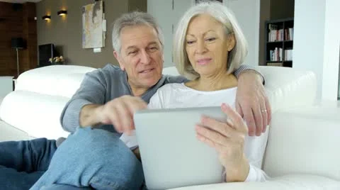 Senior couple in sofa using electronic tablet Stock Footage 14823811