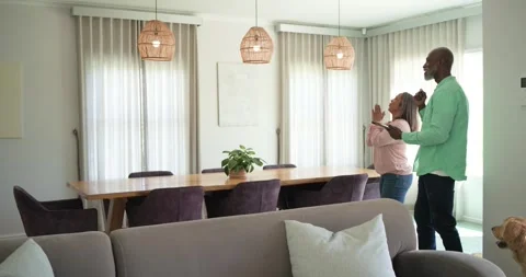 Senior couple standing on right in dining area with man using tablet, testing Stock Footage 335986692