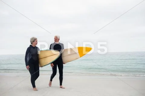 Senior couple with surfboard walking on the beach on a sunny day Stock-Fotos