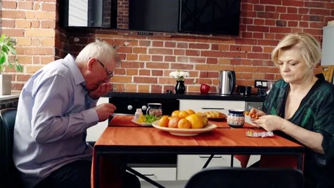 Senior couple taking pills during breakfast in ther kitchen Stock Footage 101732234