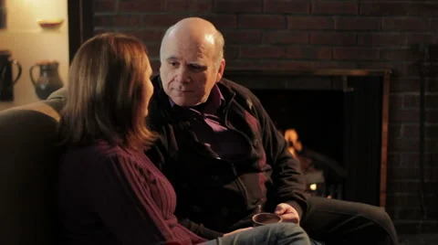 Senior couple talking in front of fireplace Stock Footage 1059250