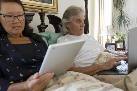Senior couple using digital tablet and laptop in bed 스톡 사진