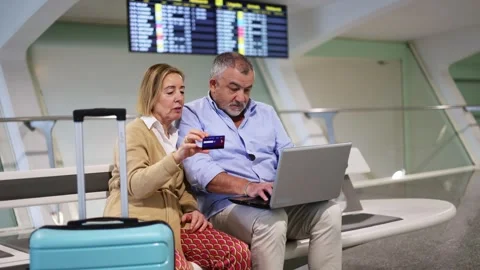 Senior couple using laptop and credit card at the airport Stock Footage 300858378