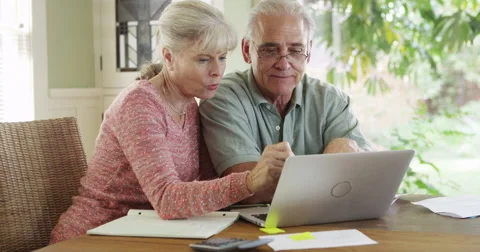 Senior couple using laptop computer to pay bills Stockbeeldmateriaal 49249405