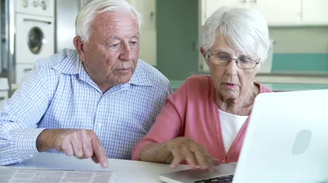 Senior Couple Using Laptop At Home In Kitchen Stock Footage