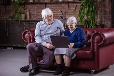 Senior couple using laptop while sitting on couch Stock Photos
