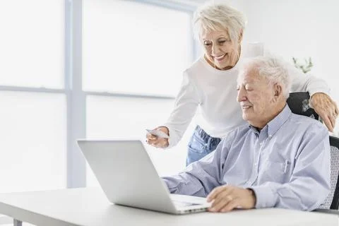 Senior couple using a laptop while sitting at the office using credit card 스톡 사진