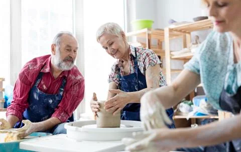 Senior couple using pottery wheel in studio Stock Photos