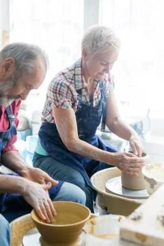 Senior couple using pottery wheels in studio Stock Photos
