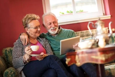 Senior couple using tablet and drinking tea Stock Photos