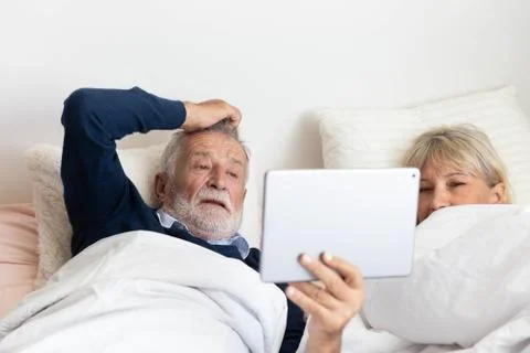 Senior couple using tablet on bed in bedroom Stock Photos