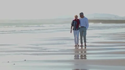 Senior couple walking barefoot on the beach Stock Footage 309565804