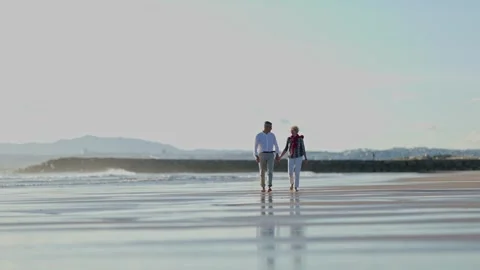 Senior couple walking on beach at sunset Stock Footage 309564665