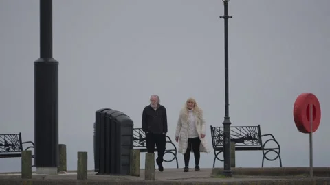 Senior Couple Walking for Exercise Along Coastal Promenade Scenery Stock Footage 332411938