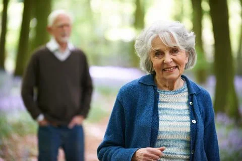 Senior Couple Walking Through Bluebell Woods Stock Photos