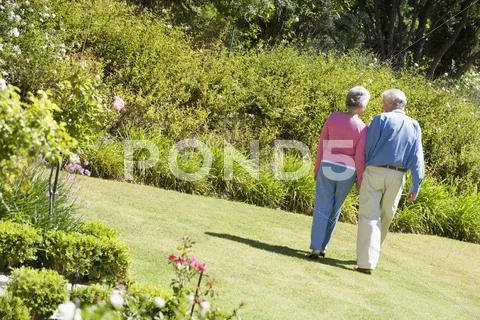 Senior couple walking through a flower garden Stock-Fotos