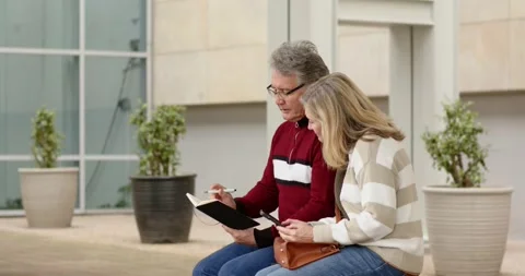 Senior couple writing planning notes by opening notebook and scrolling phone on Stock Footage 343098277