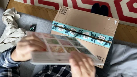 Senior curious man unboxing Amazon Prime cardboard parcel with calendar for new Stock Footage 145104269