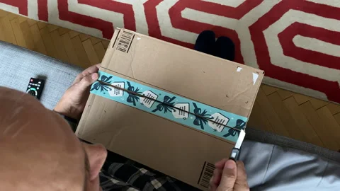 Senior curious man unboxing Amazon Prime cardboard parcel with calendar for new Stock Footage 145104313