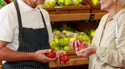 Senior customer and worker discussing vegetables in grocery store Stock Footage 52878500