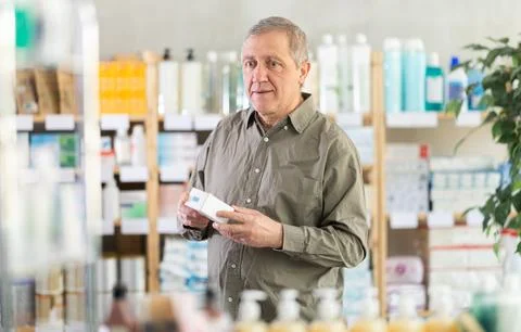 Senior customer browsing box of pills in pharmacy Stock Photos