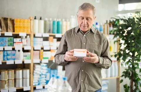 Senior customer browsing box of pills in pharmacy Stock Photos