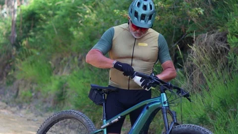 Senior cyclist drinking water and wearing gloves on electric mountain bike Stock Footage 312067583