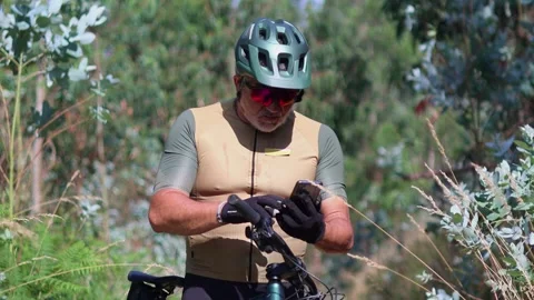 Senior cyclist using smartphone on electric mountain bike Stock Footage 312067615