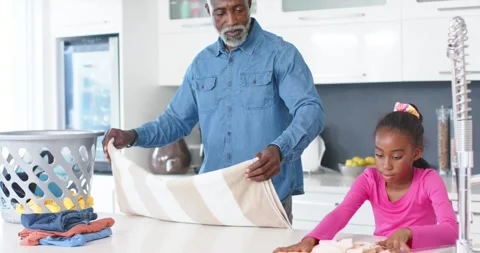 Senior dad taking towel from basket, folding with Child daughter in kitchen, Stock Footage 344385236