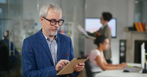 Senior developer using tablet computer for software monitoring in office of Stock Footage 99234354