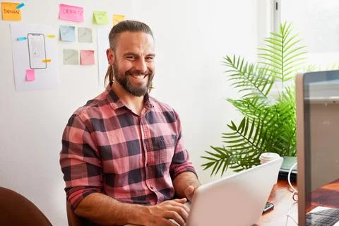 Senior developer works in open plan creative office, man bun hipster look Stock Photos