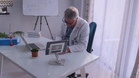 Senior doctor analyzing documents on tablet at modern medical office Stock Footage 316868609
