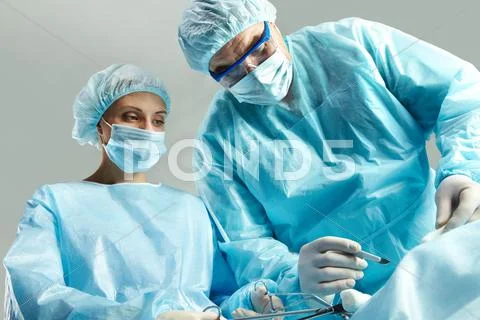 Senior doctor operating and a nurse standing with a clamp Stock Photos
