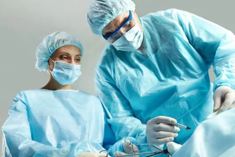 Senior doctor operating and a nurse standing with a clamp Stock Photos