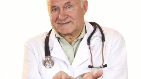 Senior doctor presenting a vibrant array of colorful pills to the camera Stock Footage 311950219
