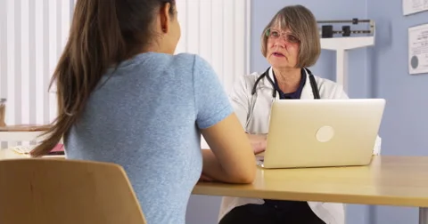 Senior doctor taking notes on laptop and talking to patient Video stock 44485877