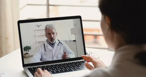 Senior doctor videoconferencing remote patient during telemedicine video call Stock Footage 128190016