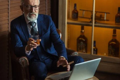 Senior dramatist looking at laptop, creating novel while sitting in pub. Stock Photos
