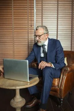 Senior dramatist looking at laptop, creating novel while sitting in pub. Stock Photos