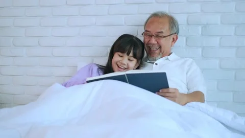 Senior elder man read a Story book with grandchild Laughing happily in bed. S Stock Footage 153348482