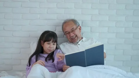 Senior elder man read a Story book with grandchild Laughing happily in bed. S Stock Footage 153443892