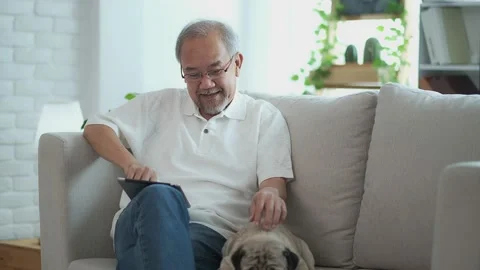 Senior elder man  using digital tablet computer modern tech relax on sofa wit Stock Footage 153351716