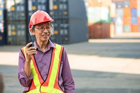 A senior elderly Asian worker engineer wearing safety vest and helmet standin Foto stock